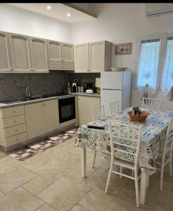 Una cocina con gabinetes blancos y una mesa y sillas. en La Casedda, en Carovigno