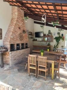 a patio with a wooden table and a brick fireplace at Chalé da Ju in Ubatuba