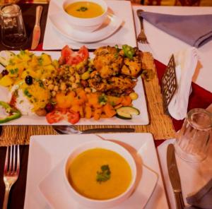 a table with a plate of food and a bowl of soup at Eternal Luxury Camp in Merzouga +49 photos