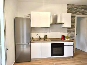 a kitchen with white cabinets and a stainless steel refrigerator at Dedè&Mimì Come a casa tua in Vasanello