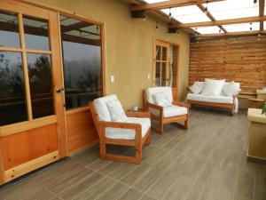 a screened in porch with two chairs and a couch at Casita Ikal in Cedro