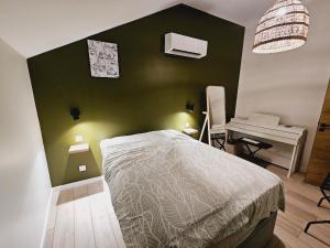 ein Schlafzimmer mit einer grünen Wand, einem Bett und einem Schreibtisch in der Unterkunft Appartement Spa et Terrasse in Dijon + 12 Fotos