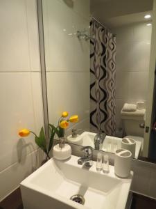 a white bathroom with a sink and a mirror at Apartments Bellas Artes in Santiago