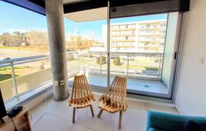 2 chaises assises devant une grande fenêtre dans l'établissement Apto 210 Un Refugio luminoso frente a la playa, à Colonia del Sacramento