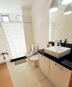 une salle de bain avec un lavabo, des toilettes et un miroir dans l'établissement Apto 210 Un Refugio luminoso frente a la playa, à Colonia del Sacramento