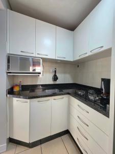 Una cocina blanca con gabinetes blancos y un microondas. en Espaço inteiro 1 km do centro da cidade, en Cascavel 9 fotos más
