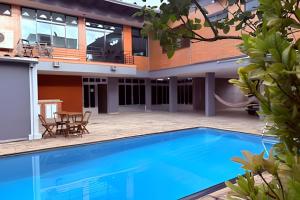 a swimming pool in front of a building with a house at Airport Stay Guarulhos – 600m Bosque Maia, Wi-Fi, Estacionamento, Sala de Espera, piscina, Check-in Facial in Vila Gopoúva