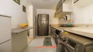 a kitchen with a washer and a stainless steel refrigerator at Apartamento em Barra dos Coqueiros a 300m da praia in Barra dos Coqueiros