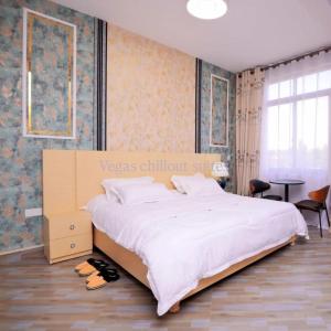 a bedroom with a large white bed and a table at Vegas Suites and SPA in Kampala