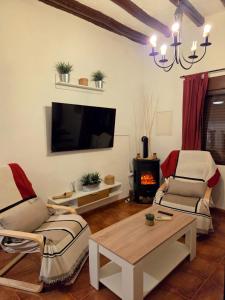 sala de estar con 2 sillas, mesa y TV en Casa Rural El Refugio, en Zuheros