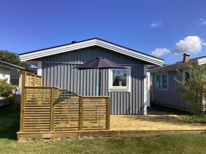 een huis met een houten terras met een paraplu bij Beach holiday home in Falkenberg in Falkenberg