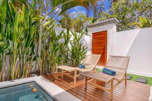 Dos sillas sentadas en una terraza junto a una piscina. en Kiki Village Private Villas, en Canggu