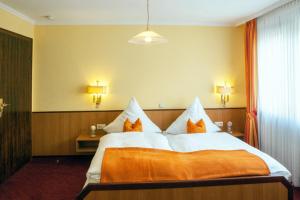 a hotel room with a large bed with orange pillows at Weinhotel Hubertus Garni in Klotten