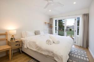 a white bedroom with a large bed and a window at Wavesong on Watts - Pet Friendly with Spa in Callala Beach