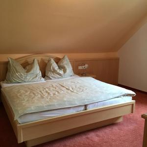 a bedroom with a bed with white sheets and pillows at Gasthof Dachsteinblick in Stainach