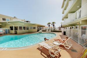 a swimming pool at a hotel with two women laying in chairs at Surfer Beach Hotel in San Diego
