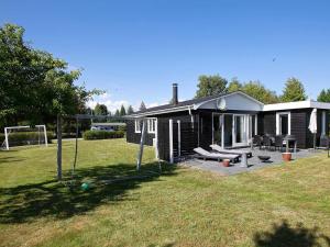 a small house with a backyard with a swing at 6 person holiday home in Væggerløse in Marielyst