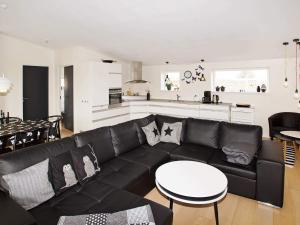 Una sala de estar con un sofá negro y una cocina. en 8 person holiday home in Hemmet-By Traum, en Hemmet