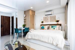 Dormitorio blanco con cama y mesa de cristal en The Signature Suite, en Ban Mai Salae 80 fotos más