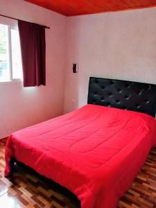 a red bed in a room with a window at Complejo Genesis MALLIN in Cueva de los Pajaritos