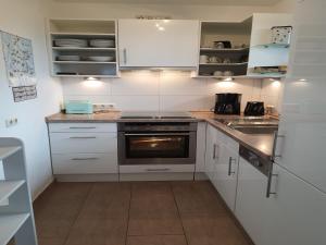 ViereggeにあるFerienhaus in Vieregge mit Terrasseの白いキャビネットとコンロ付きオーブンを備えたキッチン
