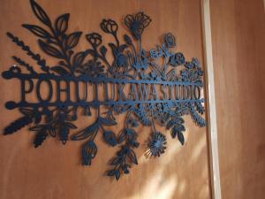 a sign on a wall with a painting of flowers at Pōhutukawa Studio in Tauranga +1 photo