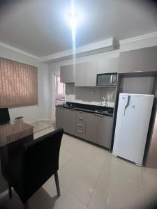 a kitchen with a refrigerator and a table with a chair at IJUÍ APART HOTEl in Ijuí