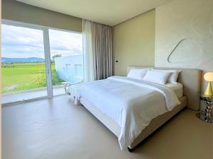 a bedroom with a large bed and a large window at MITI TIKAAN villa in Ban Muang Chum