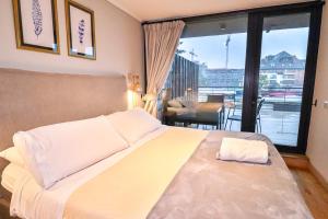 a bedroom with a large bed and a large window at HOM I Depto con Gran Terraza con Vista al Lago in Puerto Varas