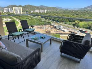 a balcony with a couch and chairs and a table at Apartamento espectacular Santa Marta in Santa Ana