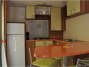 a kitchen with a table and a white refrigerator at Mobil home confortable avec terrasse, espace pour 4 personnes - API-1-52-426 in Salles