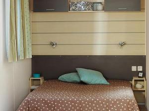 - un lit avec une tête de lit et 2 oreillers dans l'établissement Mobil-home 30m² avec terrasse à Vendays-Montalivet - API-1-52-794, à Vendays-Montalivet