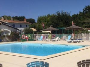une piscine avec chaises et parasols dans l'établissement Mobil-home 30m² avec terrasse à Vendays-Montalivet - API-1-52-794, à Vendays-Montalivet 27 autres photos