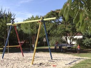 une aire de jeux avec deux balançoires et une table dans l'établissement Mobil-home 30m² avec terrasse à Vendays-Montalivet - API-1-52-794, à Vendays-Montalivet