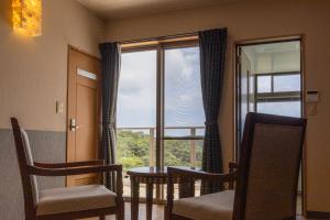 a room with a table and chairs and a window at Alpha Terrace Motobu Hills in Motobu