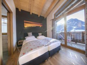 a bedroom with a bed and a large window at Chalet Stay near Krimml Waterfalls in Neukirchen am Großvenediger