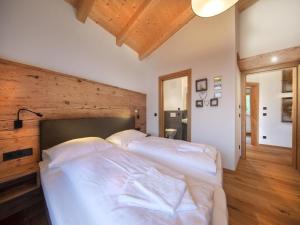 a bedroom with a large white bed with a wooden wall at Chalet in Neukirchen near Slopes in Neukirchen am Großvenediger