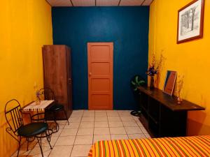 Un dormitorio con una pared azul y amarilla y una mesa y una silla. en Expresión cultural restaurante y alojamiento, en Santa Ana