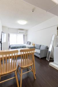 Una sala de estar con una mesa y sillas y un sofá. en Uburu Apartment, en Fukuoka