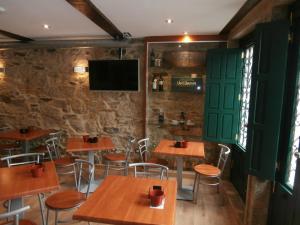un restaurante con mesas y sillas de madera y TV en Pension Via-Stella, en Santiago de Compostela
