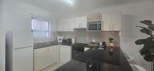 a kitchen with white cabinets and a black counter top at 118 on the Bay in Gordonʼs Bay