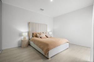 a white bedroom with a bed and two lamps at High End Home Pooraka in Ingle Farm