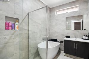 a bathroom with a shower and a tub and a sink at High End Home Pooraka in Ingle Farm +7 photos