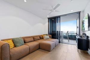 a living room with a brown couch and a balcony at Queens Wharf Luxe Retreat -Brisbane CBD, Pool, Spa in Brisbane