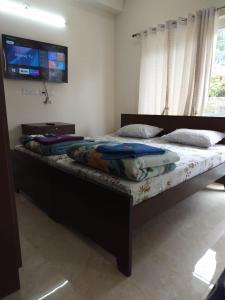 ビムタルにあるShri Rudra Home Stay - Triple Bed, Roomsの壁にテレビが付いたベッドのある寝室