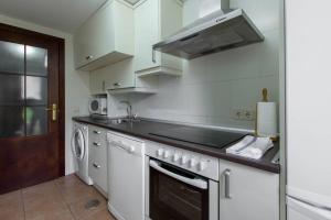 a white kitchen with a stove and a sink at Alojamientos Botica Rural in La Cabrera