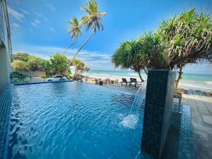 a swimming pool with a fountain in front of the beach at Sevenra Grand Beach Hotel in Ambalangoda