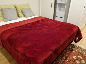 a bed with a red blanket on top of it at Brown Palace in Auckland