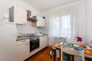 a kitchen with white cabinets and a table and a table and chairs at Apartments Dorotea in Krk