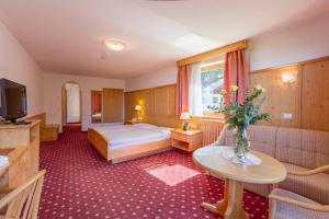 een hotelkamer met een bed en een televisie bij Hotel Plunger in Castelrotto